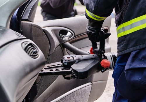 A dedicated team of professional firefighters employs specialized tools to cut and break through vehicle wreckage, showcasing their skilled collaboration and swift response in rescuing individuals involved in a car accident.
